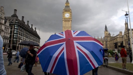 A pedestrian shelters from the rain beneath a Union flag themed umbrella as they walk near the Big Ben clock face and the Elizabeth Tower at the Houses of Parliament in central London on June 25, 2016, following the pro-Brexit result of the UK's EU referendum vote.
The result of Britain's June 23 referendum vote to leave the European Union (EU) has pitted parents against children, cities against rural areas, north against south and university graduates against those with fewer qualifications. London, Scotland and Northern Ireland voted to remain in the EU but Wales and large swathes of England, particularly former industrial hubs in the north with many disaffected workers, backed a Brexit. / AFP PHOTO / JUSTIN TALLIS        (Photo credit should read JUSTIN TALLIS/AFP/Getty Images)