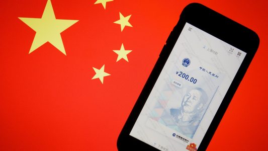 FILE PHOTO: China's official app for digital yuan is seen on a mobile phone placed in front of an image of the Chinese flag, in this illustration picture taken October 16, 2020. REUTERS/Florence Lo